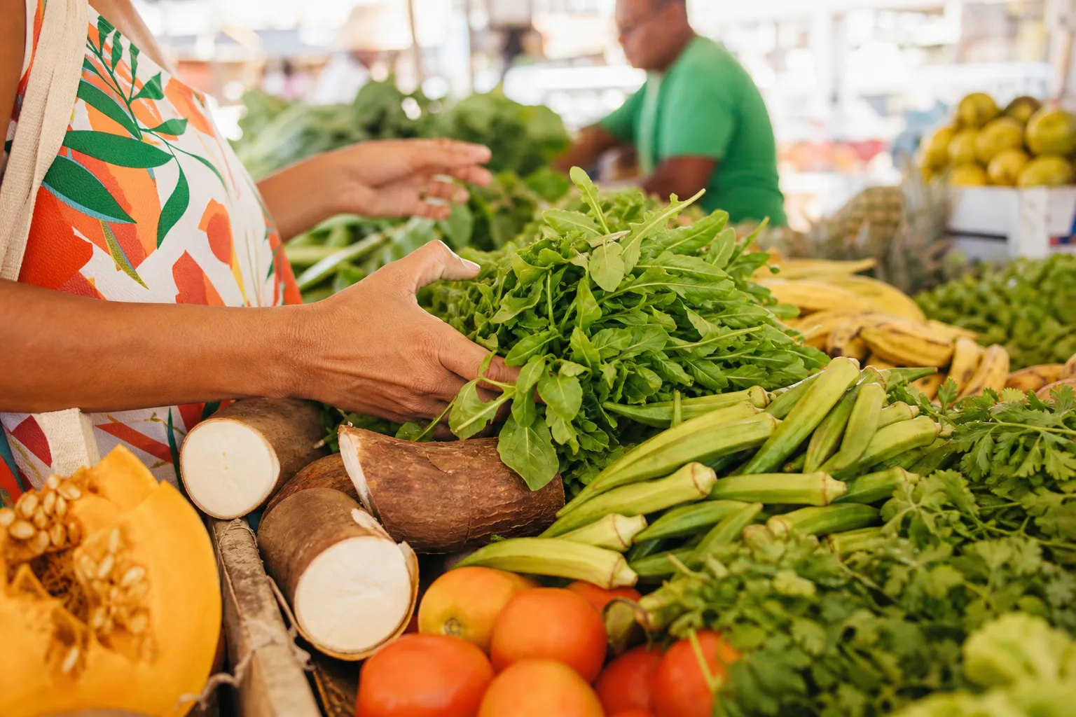 Mãos escolhendo verduras, legumes e frutas em uma feira livre