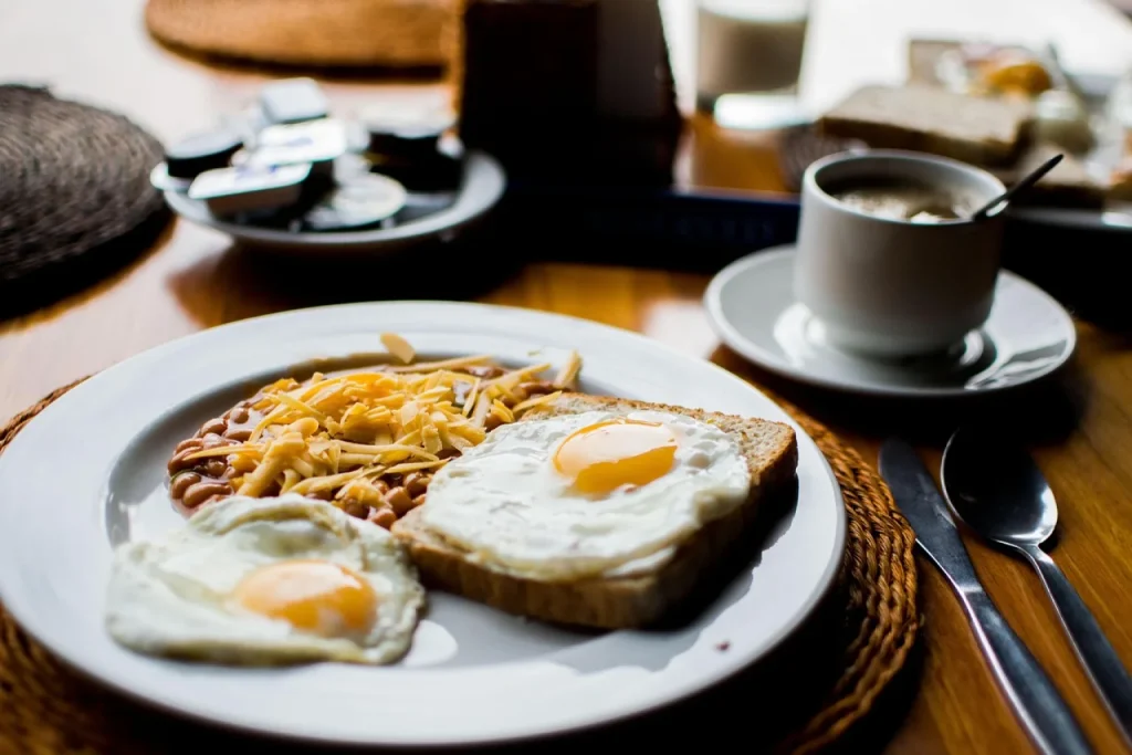Mesa de café da manhã nordestino com cuscuz de milho, ovo mexido, queijo coalho, macaxeira cozida, mamão, banana e café